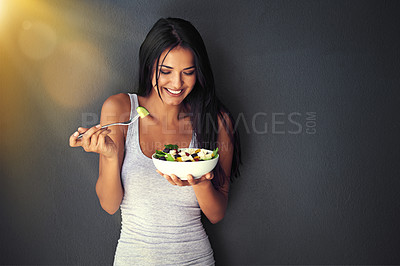 Buy stock photo Shot of a healthy young woman eating a salad against a gray background