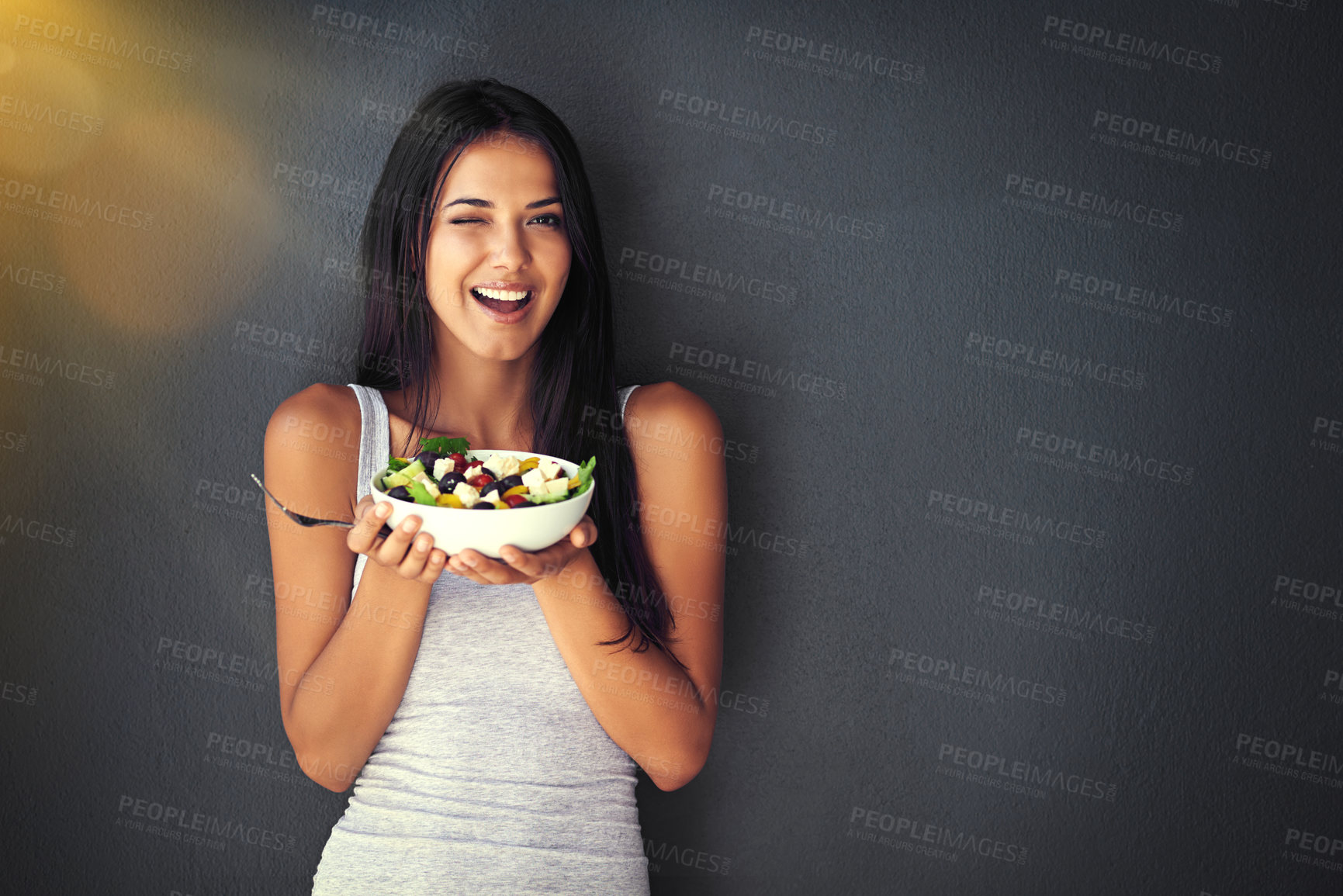 Buy stock photo Woman wink with salad, healthy food and nutrition, portrait and vegetables isolated on wall background. Happy, body and health with wellness, diet and female model to lose weight with mockup space