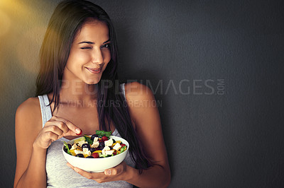 Buy stock photo Portrait of a healthy young woman eating a salad against a gray background