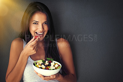 Buy stock photo Woman is eating a tomato from salad, portrait and healthy food with nutrition and vegetables on wall background. Happy, vegan and health, female model on diet to lose weight and mockup space