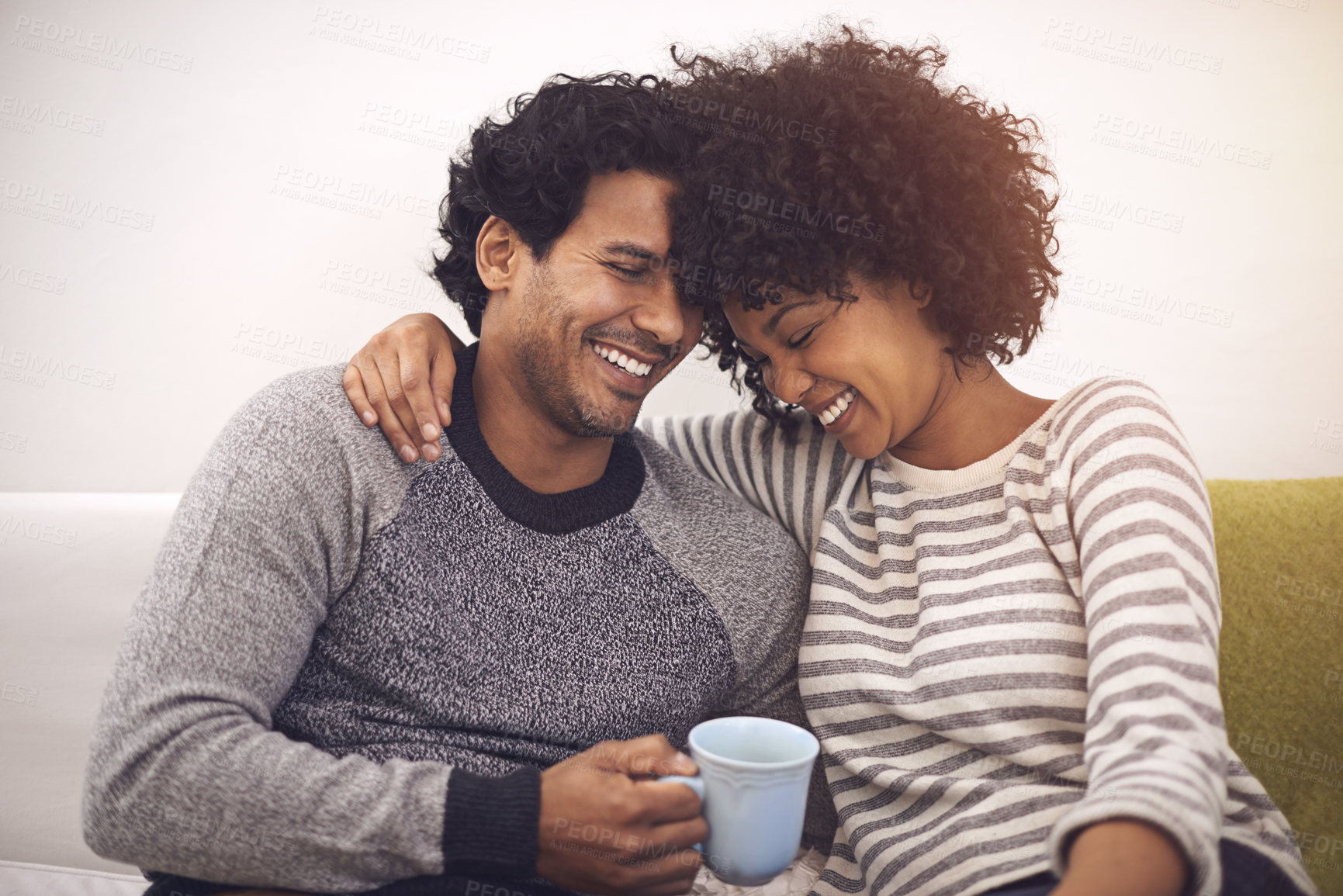 Buy stock photo Couple, couch and hug for care and tea in home, smile and proud of marriage and commitment. Happy people, embrace and laughing on sofa in living room on weekend, support and trust in relationship