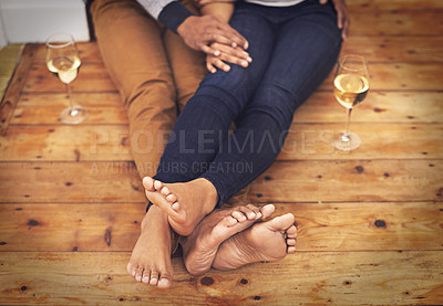 Buy stock photo Wine, feet and couple relaxing together on wooden floor for romantic date at modern home. Love, champagne and closeup of man and woman legs with alcohol drink sitting on ground at apartment.