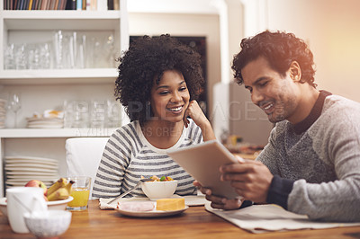 Buy stock photo Shot of a couple using a digital tablet while having breakfast at home