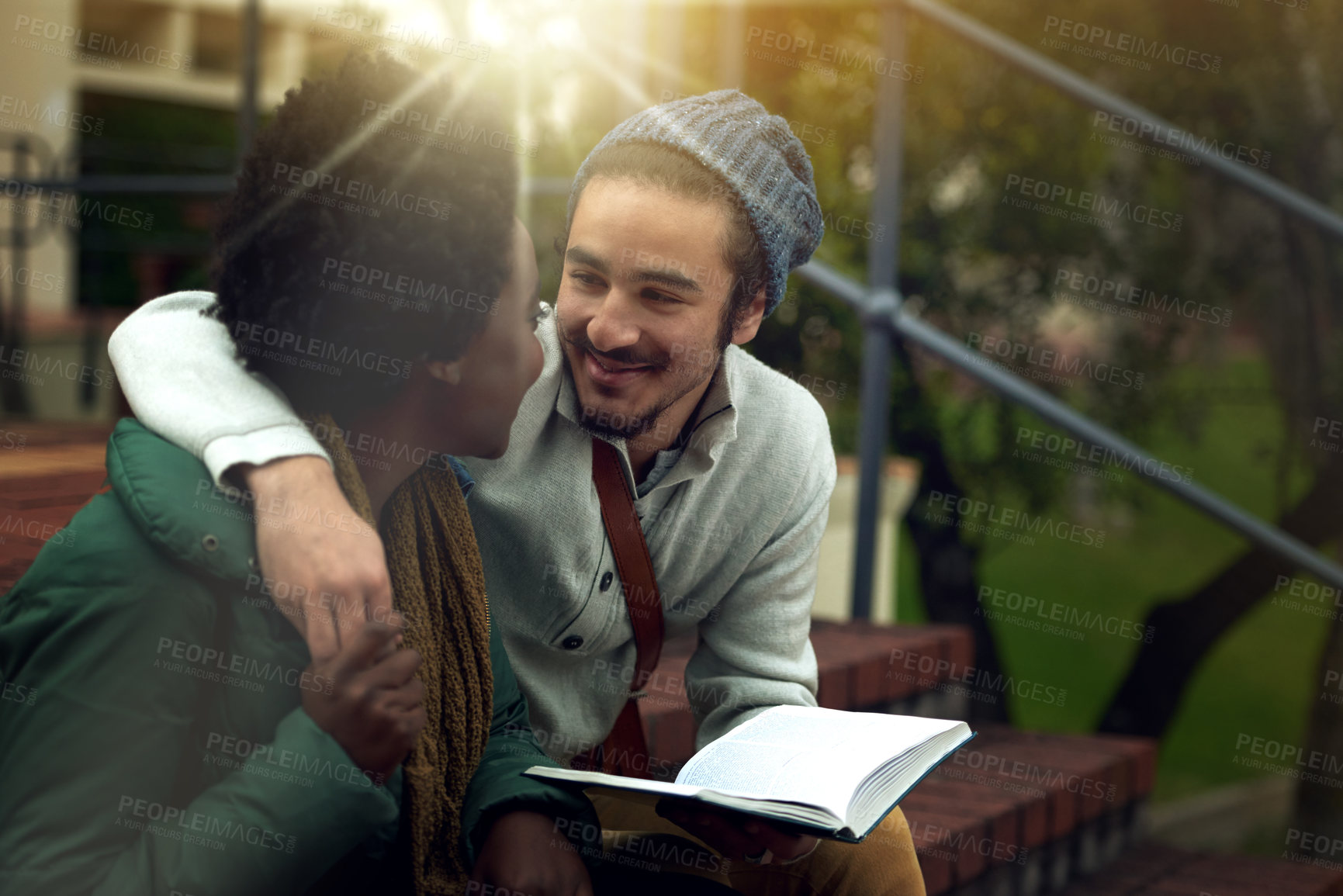 Buy stock photo Book, study and interracial couple together on campus with hug, bag and morning romance at university. College, students and love on steps, man and woman with diversity, education and happy embrace.