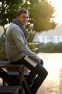 Buy stock photo Student, man and outdoor on campus with book in smile, study and prepare for exam with revision notes. Portrait, college and academic for assignment with textbook for education and learning.