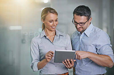 Buy stock photo Cropped shot of two businesspeople working on a digital tablet