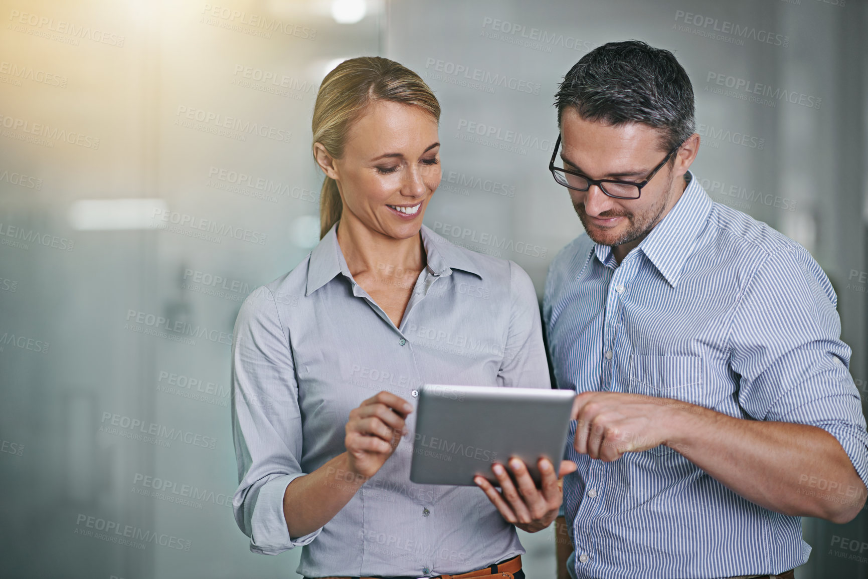 Buy stock photo Cropped shot of two businesspeople working on a digital tablet