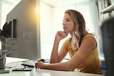 Buy stock photo Shot of a young woman working on a computer in her home office