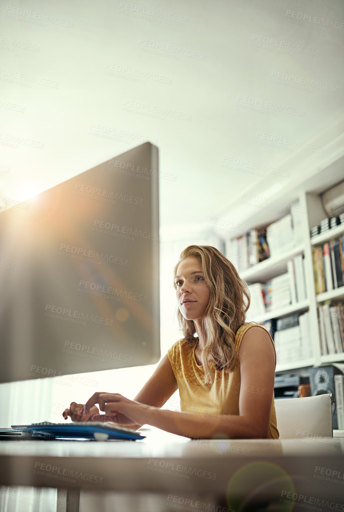 Buy stock photo Shot of a young woman working on a computer in her home office