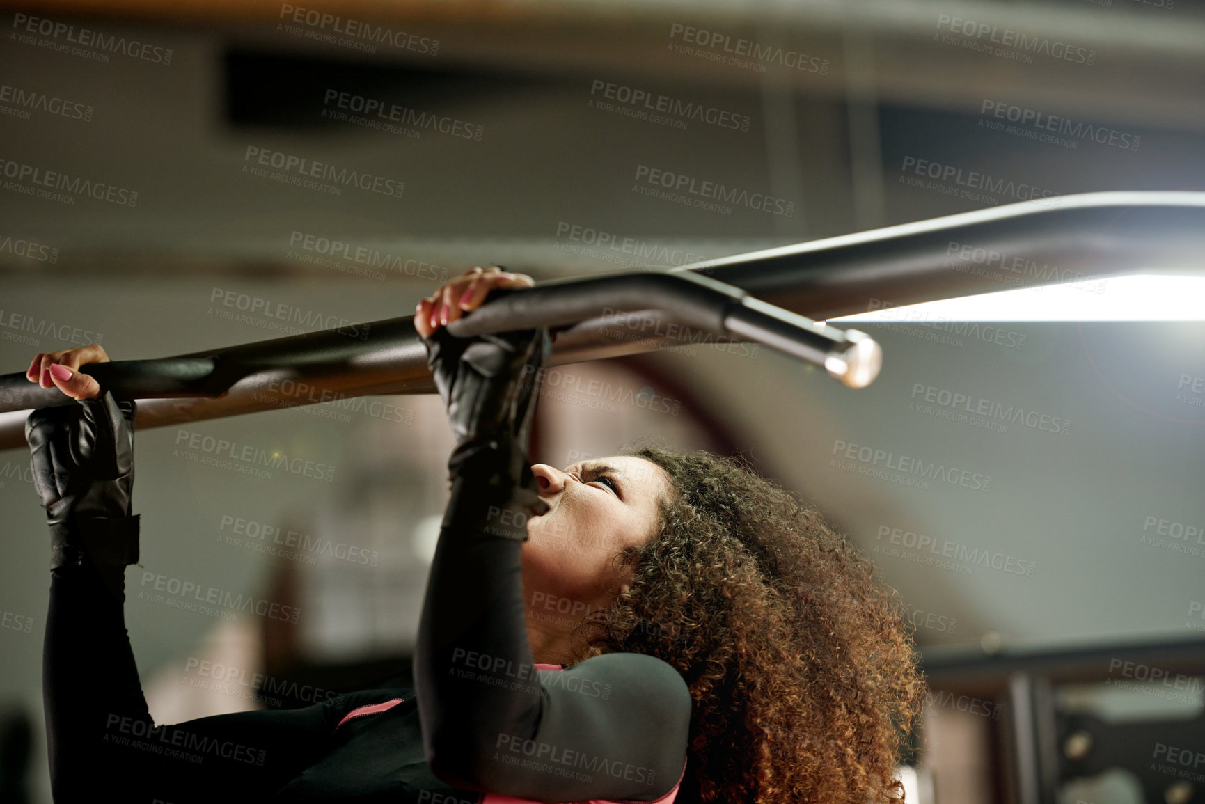 Buy stock photo Shot of a young woman doing pull ups at the gym