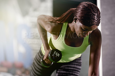 Buy stock photo Shot of a young woman lifting weights at the gym