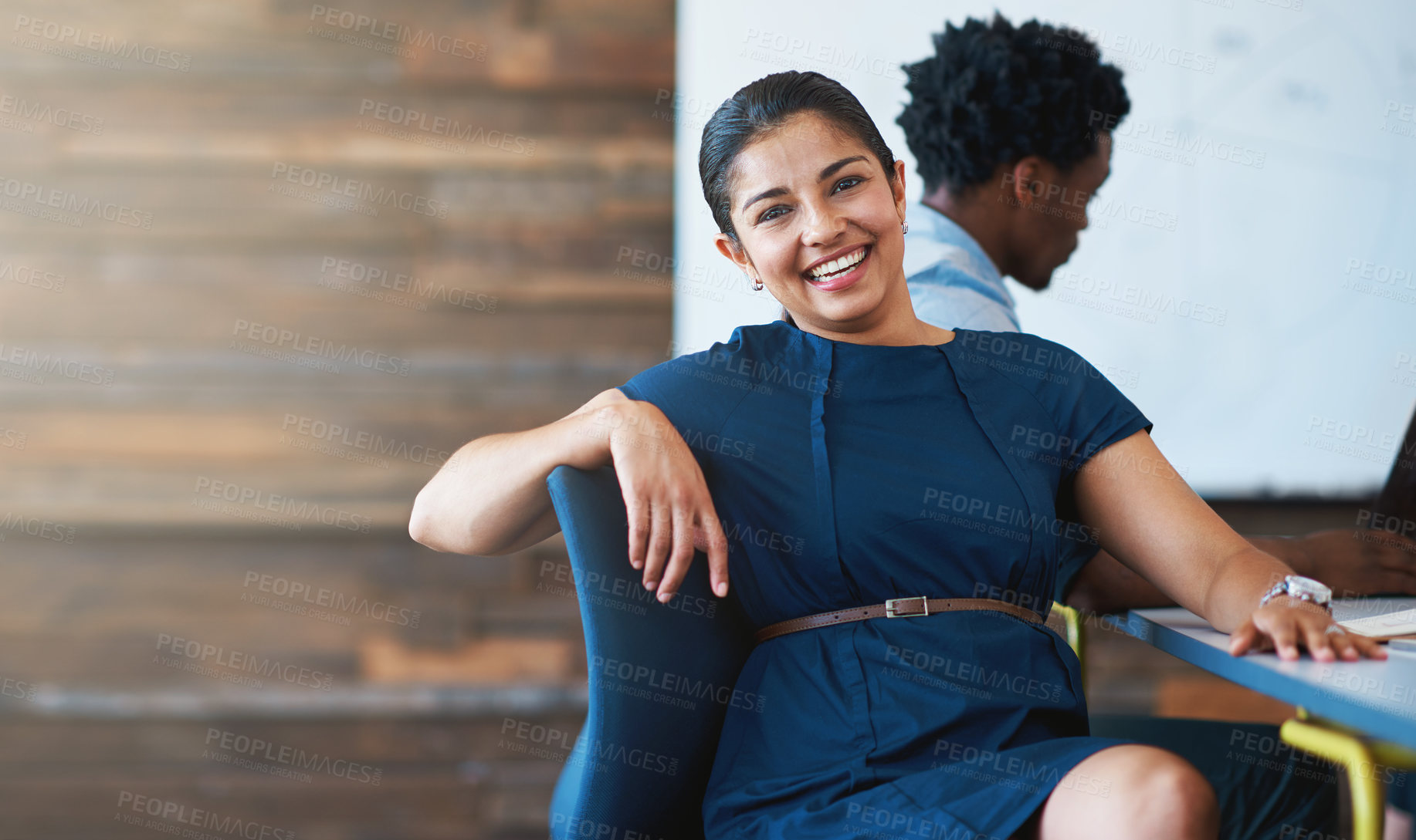 Buy stock photo A young businesswoman sitting in an office chair with a colleague in the background