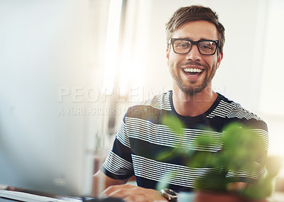 Buy stock photo Portrait of a designer looking pleased while working at his computer