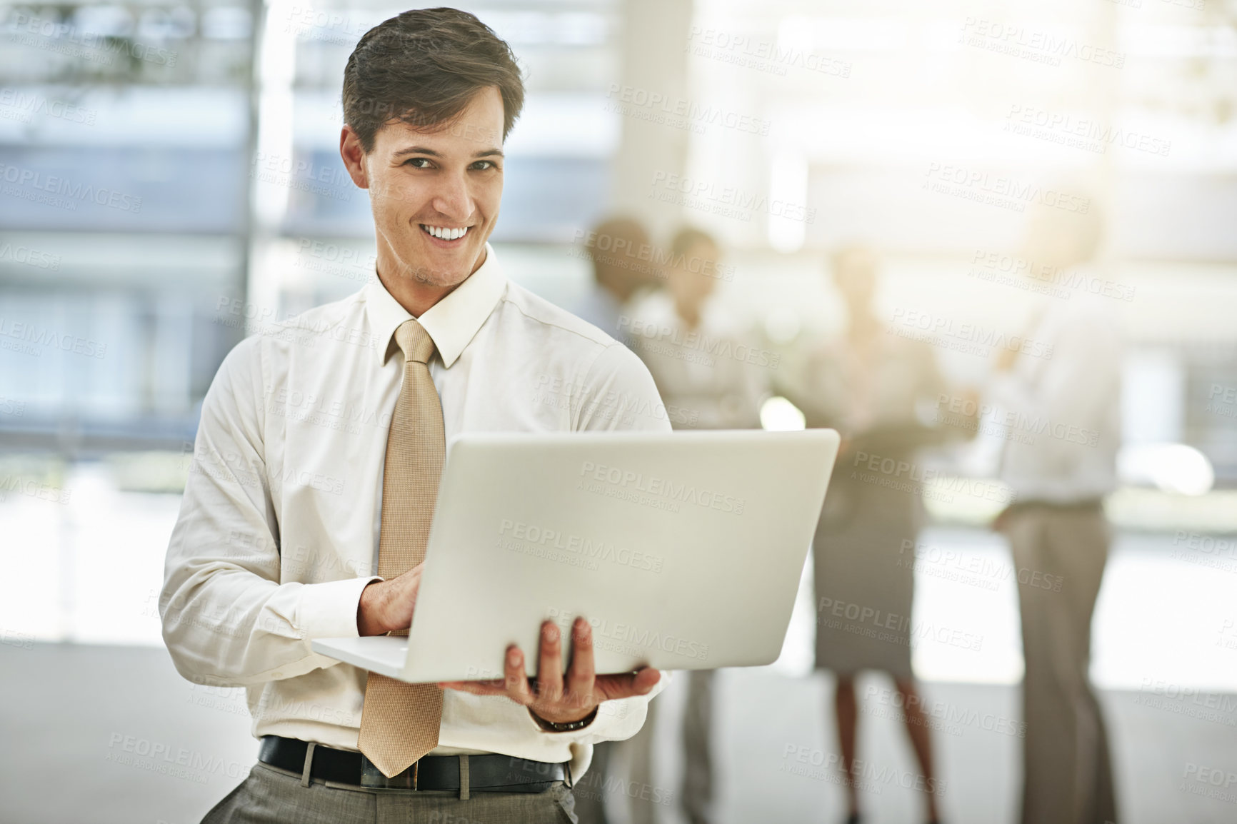 Buy stock photo Cropped portrait of a young businessman using a laptop with his colleagues in the background