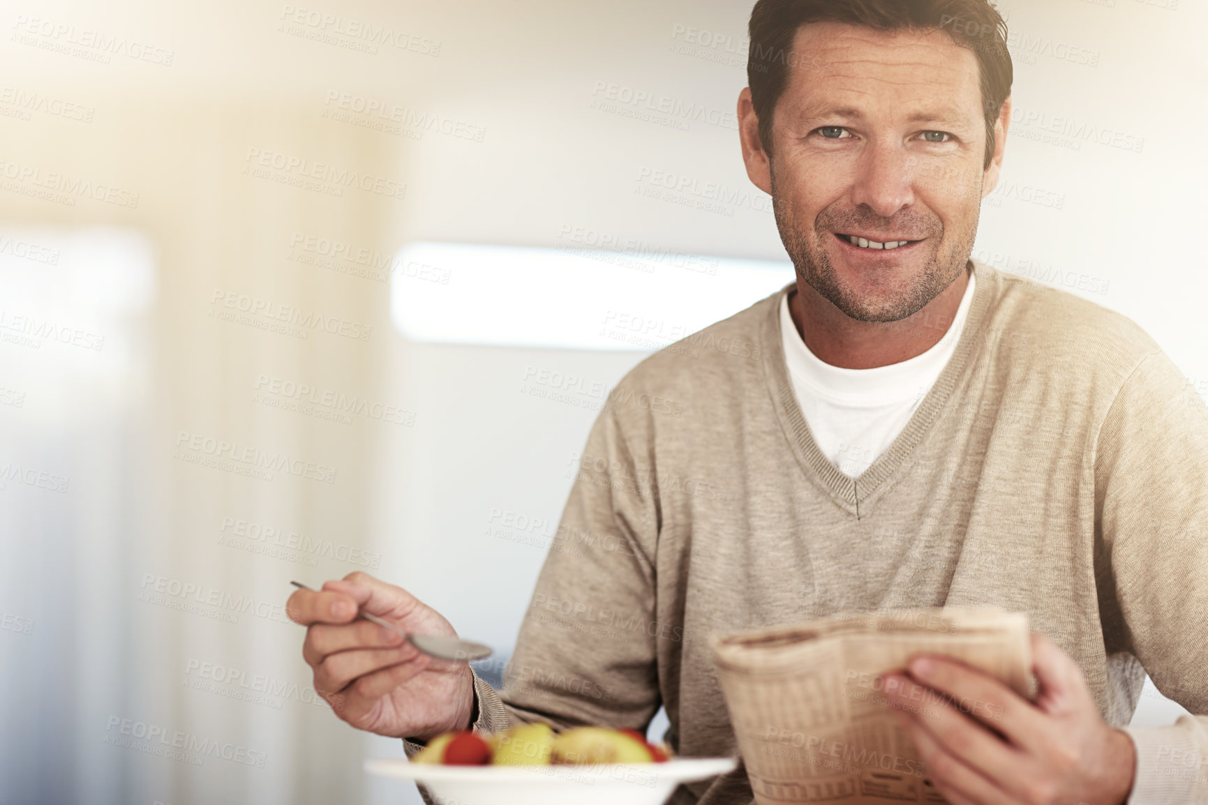 Buy stock photo Cropped portrait of a man using his tablet while eating breakfast at home