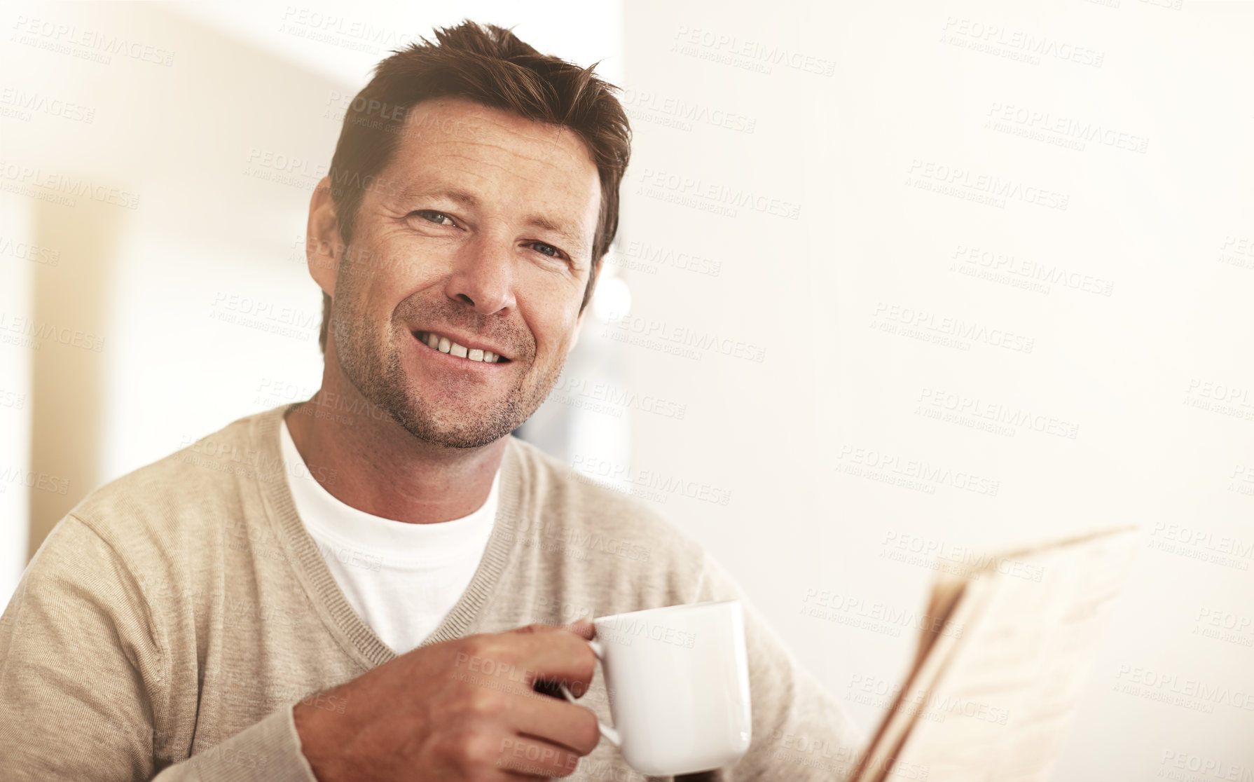 Buy stock photo Cropped portrait of a man drinking coffee while reading the paper at home