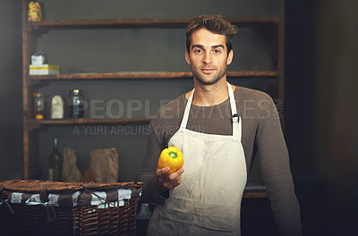 Buy stock photo Shot of a young man holding a yellow pepper in his kitchen