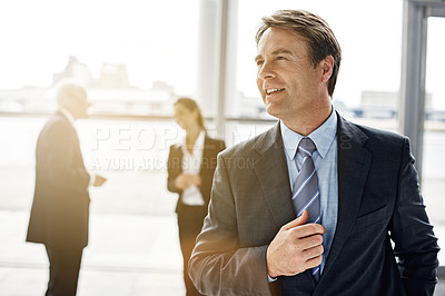 Buy stock photo Cropped shot of a businessman standing a lobby with his colleagues in the background