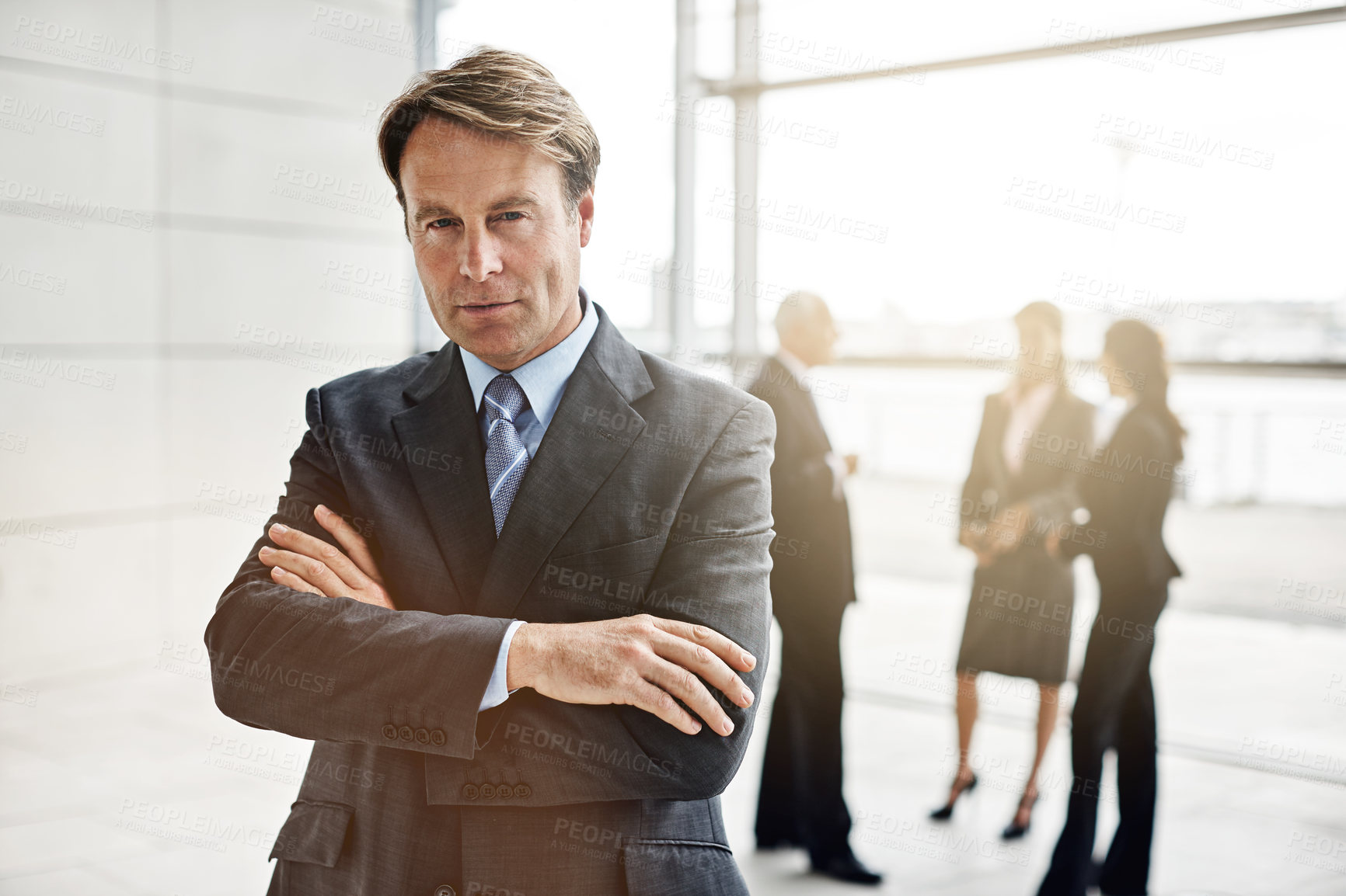 Buy stock photo Cropped portrait of a businessman standing a lobby with his colleagues in the background