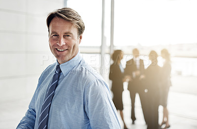 Buy stock photo Cropped portrait of a businessman standing a lobby with his colleagues in the background