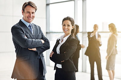 Buy stock photo Cropped portrait of two businesspeople standing a lobby with their colleagues in the background