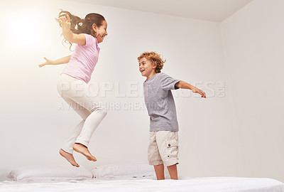 Buy stock photo Shot of two little children jumping on a bed