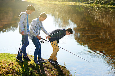 Buy stock photo Shot of a group of young boys fishing by a lake