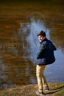 Buy stock photo Shot of a young boy fishing by a lake