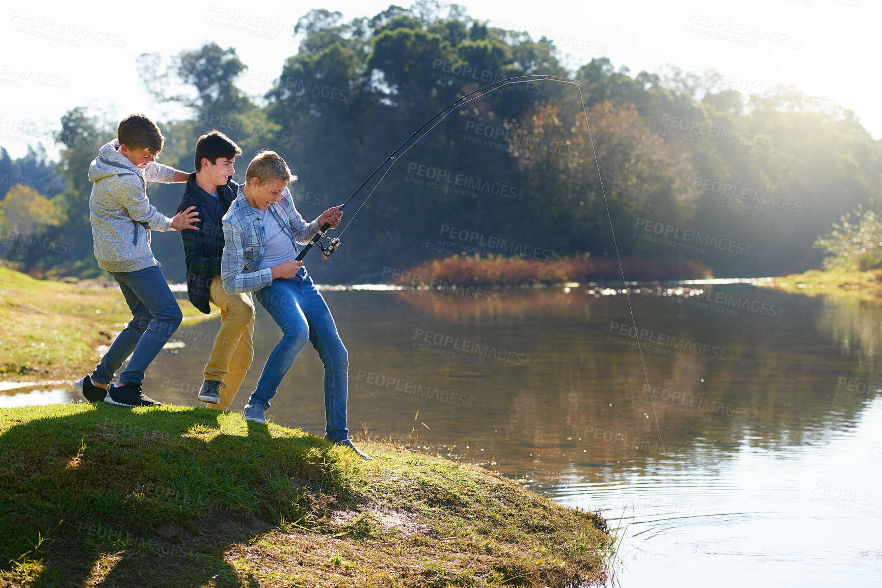 Buy stock photo Shot of a group of young boys fishing by a lake