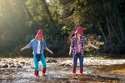 Buy stock photo Shot of two young girls playing in a river