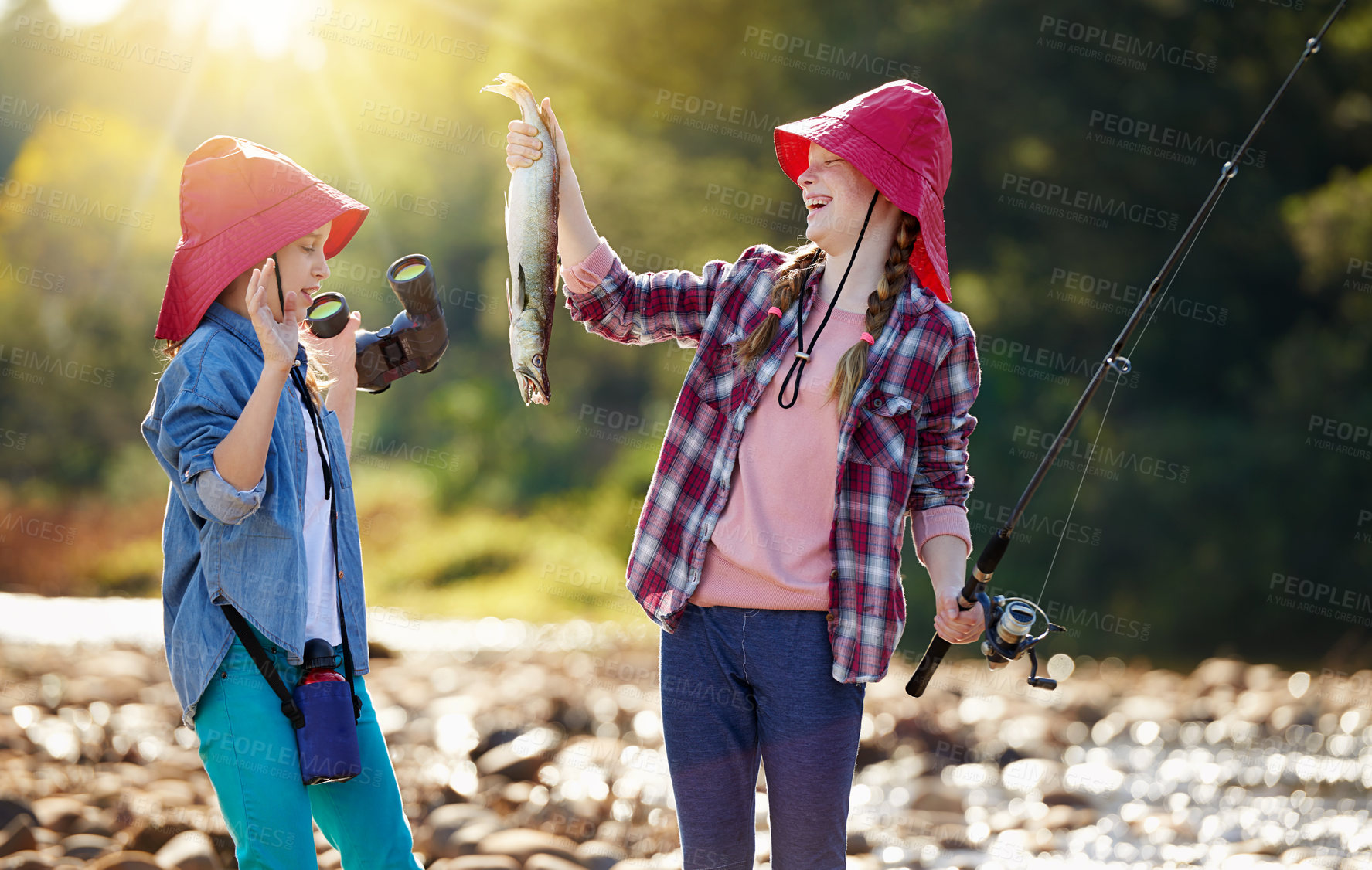 Buy stock photo Countryside, binocular and fish with children in river on holiday break, vacation or adventure as hobby. Sunshine, girls or siblings and fishing rod in water on weekend trip, outdoor and nature