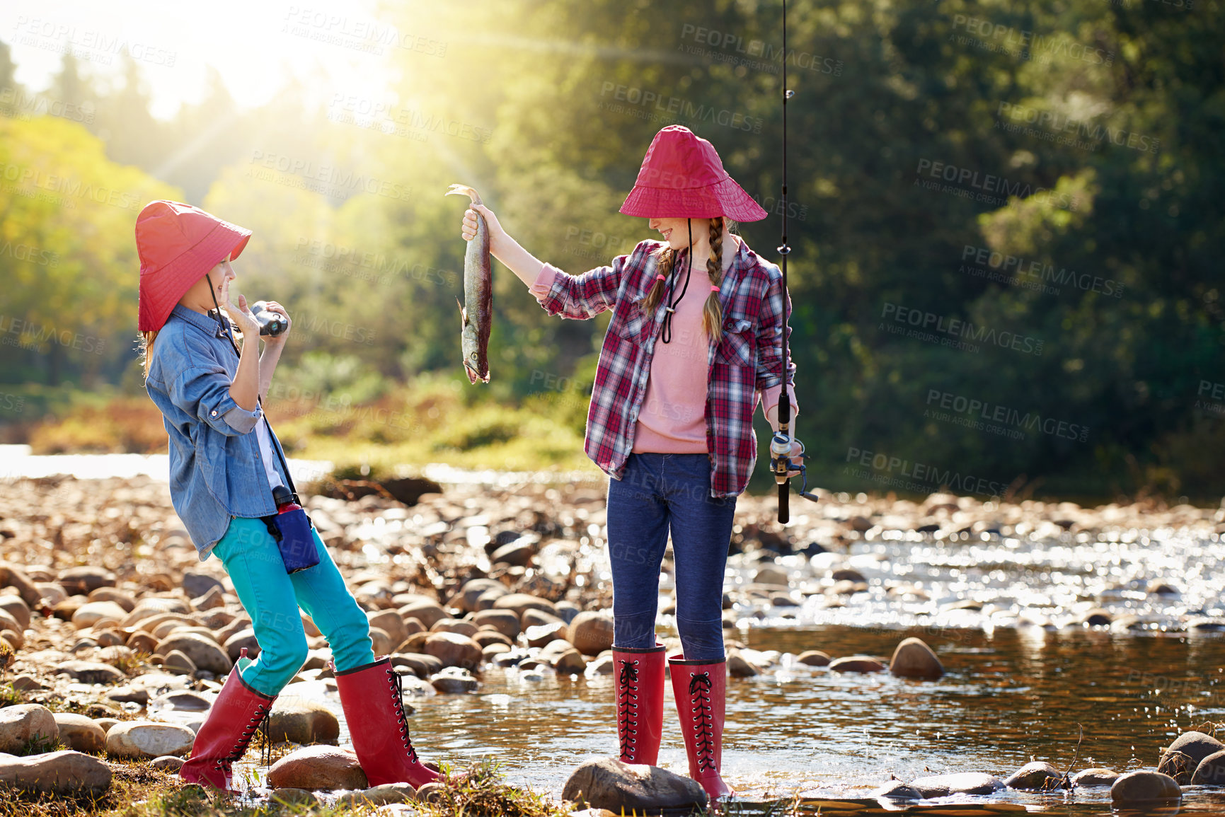 Buy stock photo Countryside, binocular and fish with girls in river on holiday break, vacation or adventure as hobby. Sunshine, happy children or siblings and fishing rod on weekend trip, outdoor and nature to bond