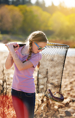 Buy stock photo Shot of a young girl looking at the fish she caught with her net