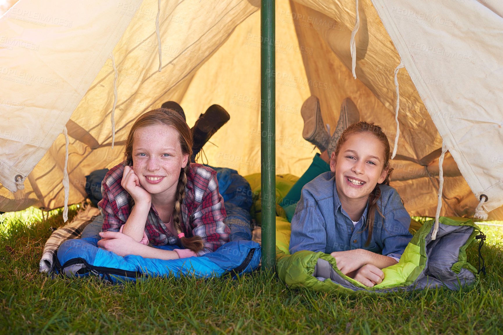 Buy stock photo Two young girls lying on their sleeping bags in their tent