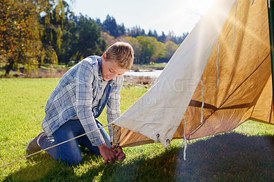 Buy stock photo Boy, camping and pitching tent in outdoor for vacation with family adventure, fresh air and lens flare. Smiling kid, shelter and green grass for safety with fun, summer holiday and sunshine in Canada