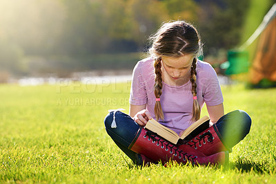 Buy stock photo Shot of a teenage girl relaxing with a book on the grass