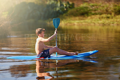 Buy stock photo Shot of a teenage boy rowing his kayak on a lake