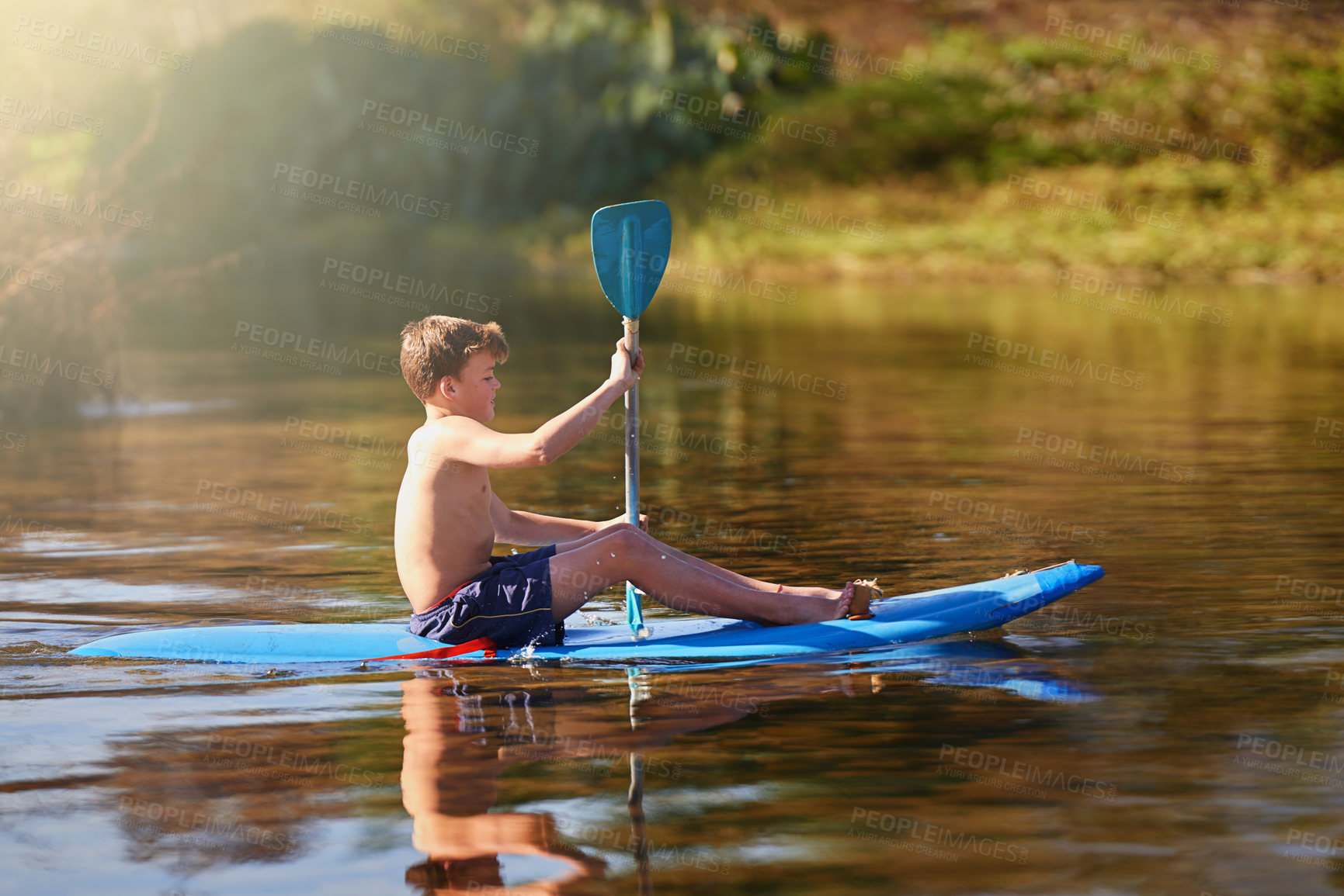 Buy stock photo Shot of a teenage boy rowing his kayak on a lake