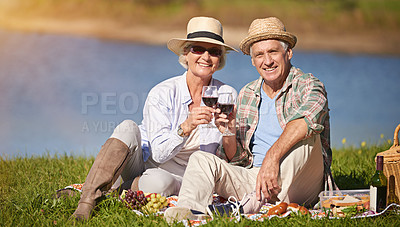 Buy stock photo Senior couple, happy and toast wine glasses for picnic date, sundowners or lunch by the lake. Elderly man, relaxed and mature woman smiling for retirement, relationship celebration or bonding 