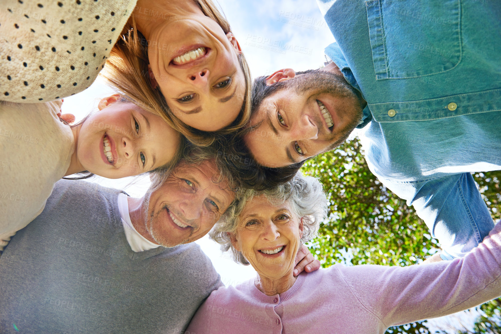 Buy stock photo Face portrait, smile and circle of happy family hug, grandparents and parents bond with kid in nature park. Solidarity care, blue sky or bottom view of people smile in garden, forest or outdoor woods