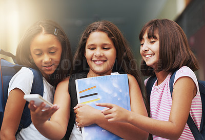 Buy stock photo Elementary school, group of friends or girls with phone, reading social media notification or download digital app. Diversity, students or happy kids pointing to mobile, tech or typing online for fun