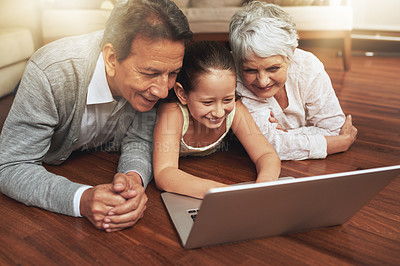 Buy stock photo Shot of a little girl showing her grandparents something on a laptop