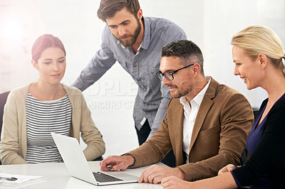 Buy stock photo A group of businesspeople working together around a laptop