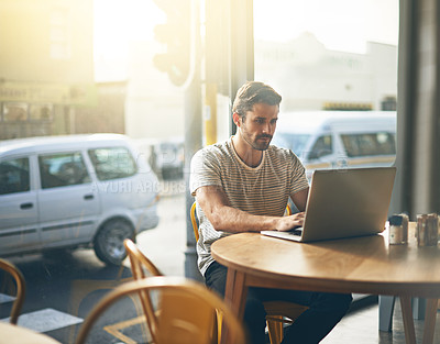 Buy stock photo Shot of a young man working on his laptop in a coffee shop