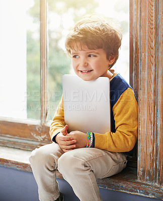 Buy stock photo Cropped shot of a young boy using a tablet while sitting on a windowsill
