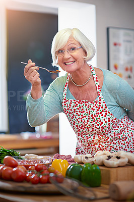 Buy stock photo Shot of a senior woman tasting the food she is cooking