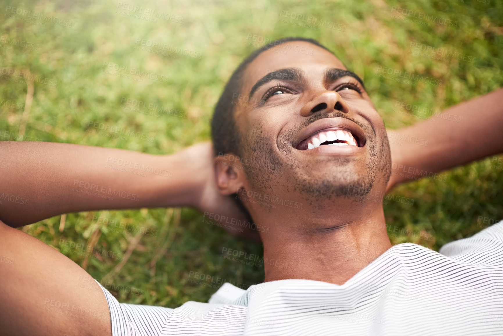 Buy stock photo Shot of a young man relaxing on the grass outdoors