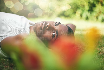 Buy stock photo Man, portrait and lying on grass while resting, smile and enjoy summer or outdoor. Black person, relax and sunshine after holiday or vacation, comfortable and happiness in park or nature flare