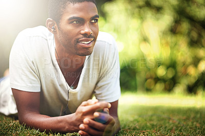 Buy stock photo Shot of a young man listening to music outdoors