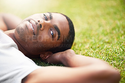Buy stock photo Portrait, relax and black man on grass in garden of summer home for peace, wellness or mindfulness. Face, nature and field with happy young person lying on green ground from above for break or rest